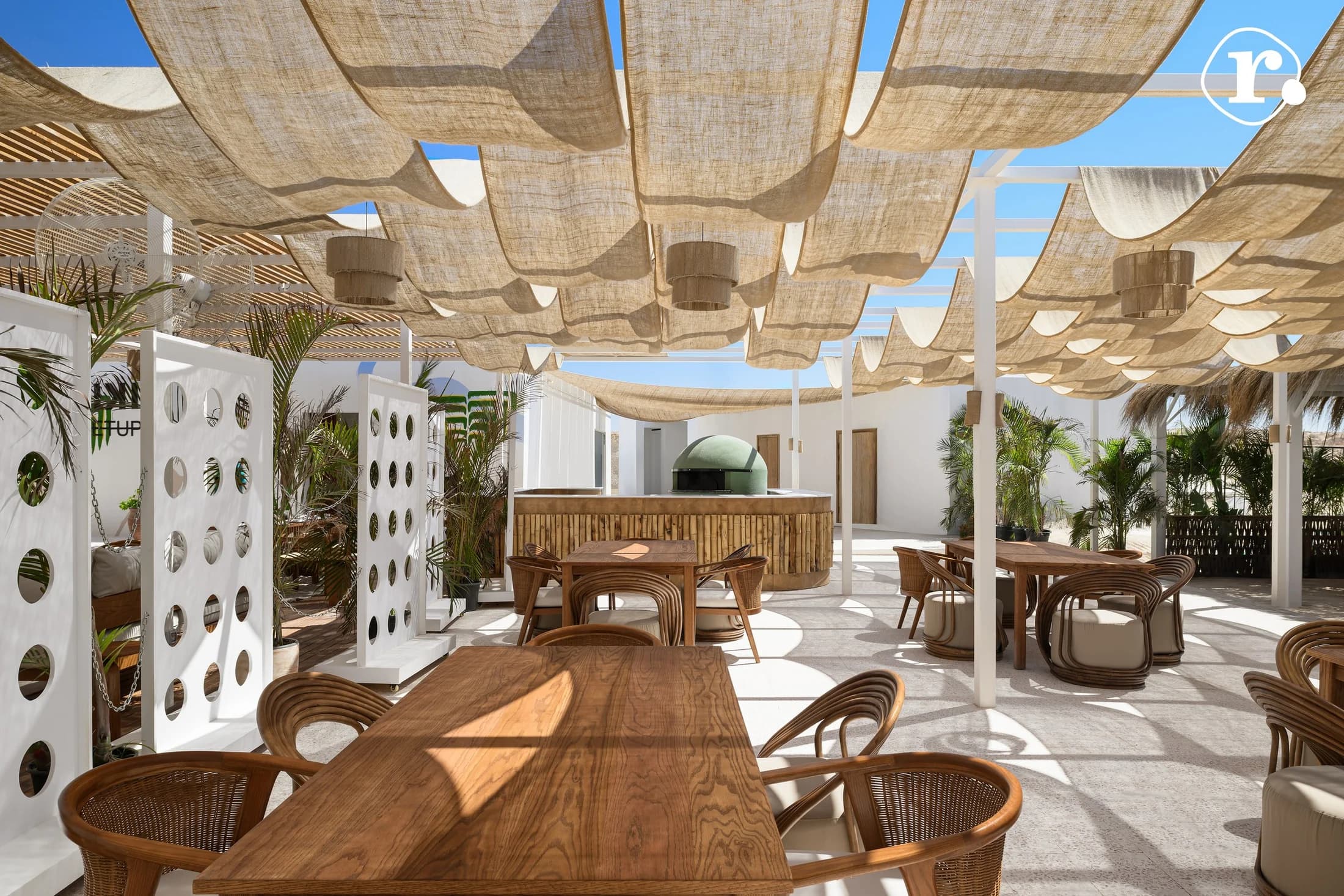 Long communal table beneath woven shades and hanging lights