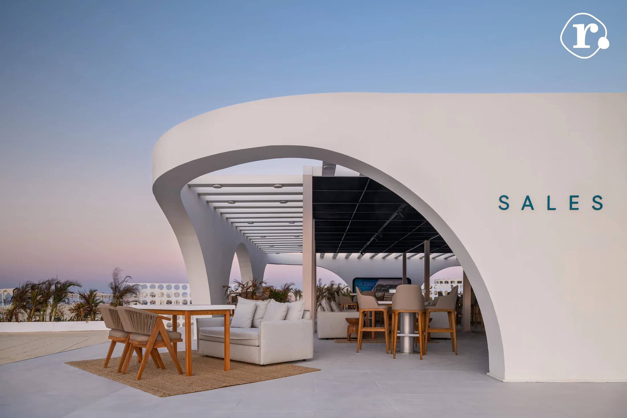 Curved sales pavilion and outdoor seating at sunset
