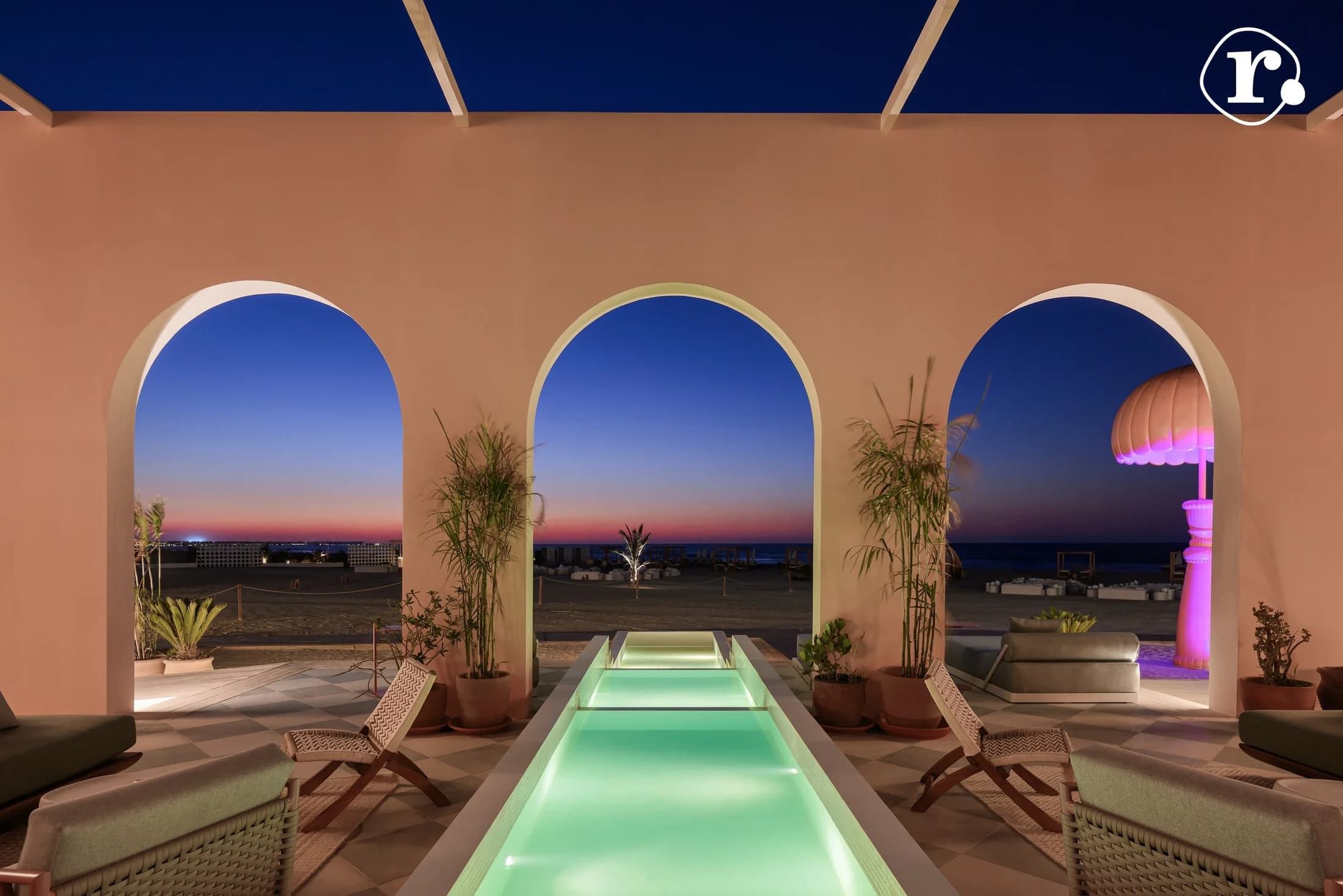 Glowing pool and sunset sea view framed by three arches